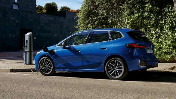 BMW 2 Serisi Active Tourer 230e plug-in hybrid U06, şarj istasyonunda park halinde görünüm BMW 2 Serisi Active Tourer 230e plug-in hybrid U06, Metalik M Mavi/Portimao, şarj istasyonunda yandan görünüm