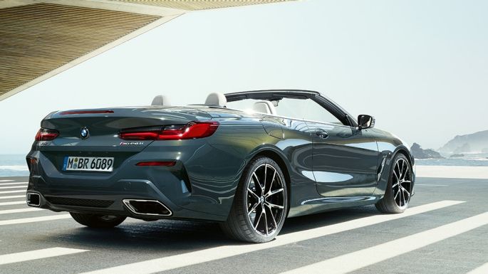 BMW M850i xDrive Cabrio, arkadan görünüm. Açık softtop ile metalik Gri/Dravit BMW M850i xDrive, okyanus manzarası önünde park halinde, arkadan görünüm.