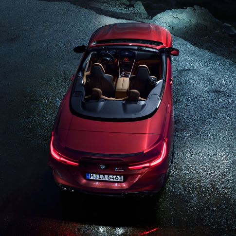 BMW M8 Competition Cabrio, kuş bakışı görünüm. Gece asfalt üzerinde açık softtop ile metalik Kırmızı/Motegi BMW M8 Competition Cabrio, kuş bakışı görünüm.