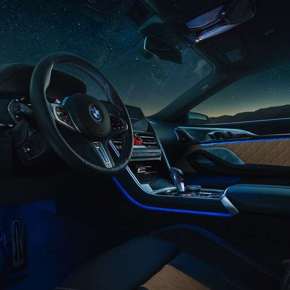 BMW M8 Competition Coupé, kokpit. BMW M8 Competition Coupé, M deri direksiyon ve mavi ortam aydınlatmasıyla kokpitin gece görünümü.