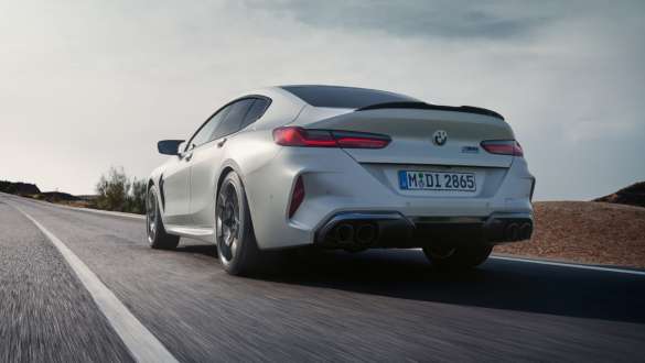 M xDrive BMW M8 Competition Gran Coupé F93 BMW M8 Competition Gran Coupé F93 BMW Individual Metalik Beyaz/Frozen Brilliant sürüş sırasında alçak açıdan arkadan görünüm M xDrive