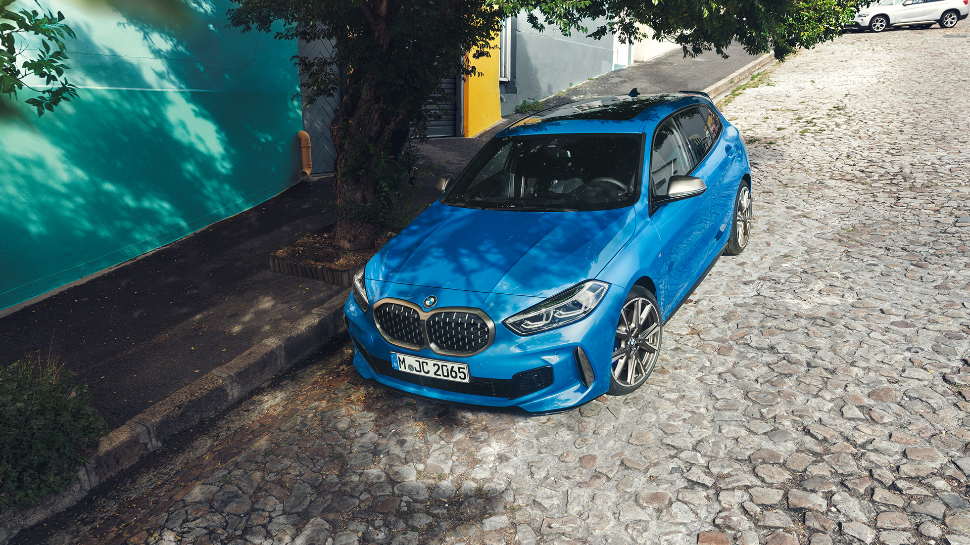 BMW 1 Serisi, yol kenarında. Metalik Mavi/Misano rengi BMW 1 Serisi’nin yol kenarında kuş bakışı görünümü.