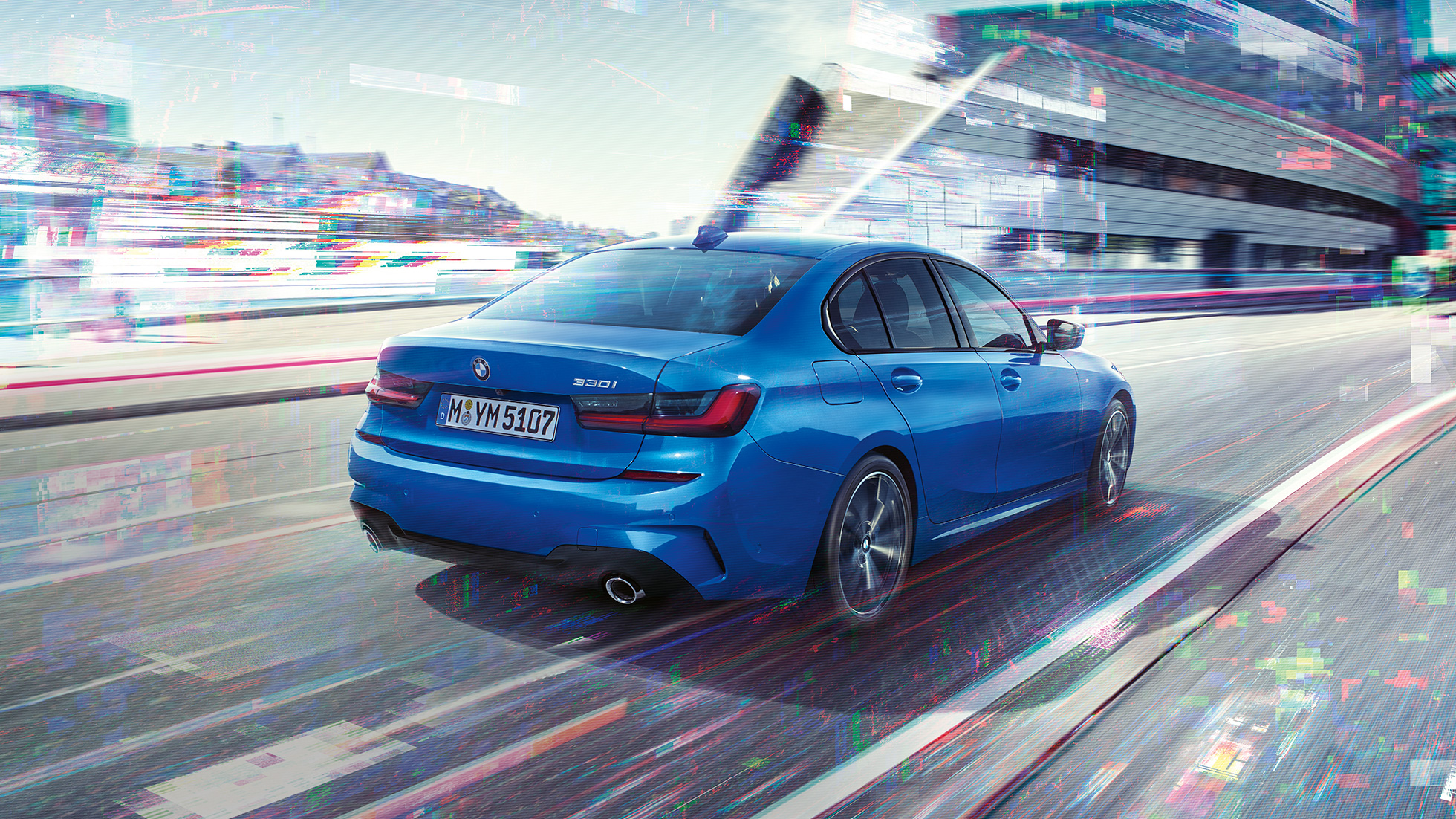 BMW 3 Serisi Sedan, arka yandan görünüm. BMW 3 Serisi Sedan’ın şehir manzarası önünde gündüz arkadan görünümü.