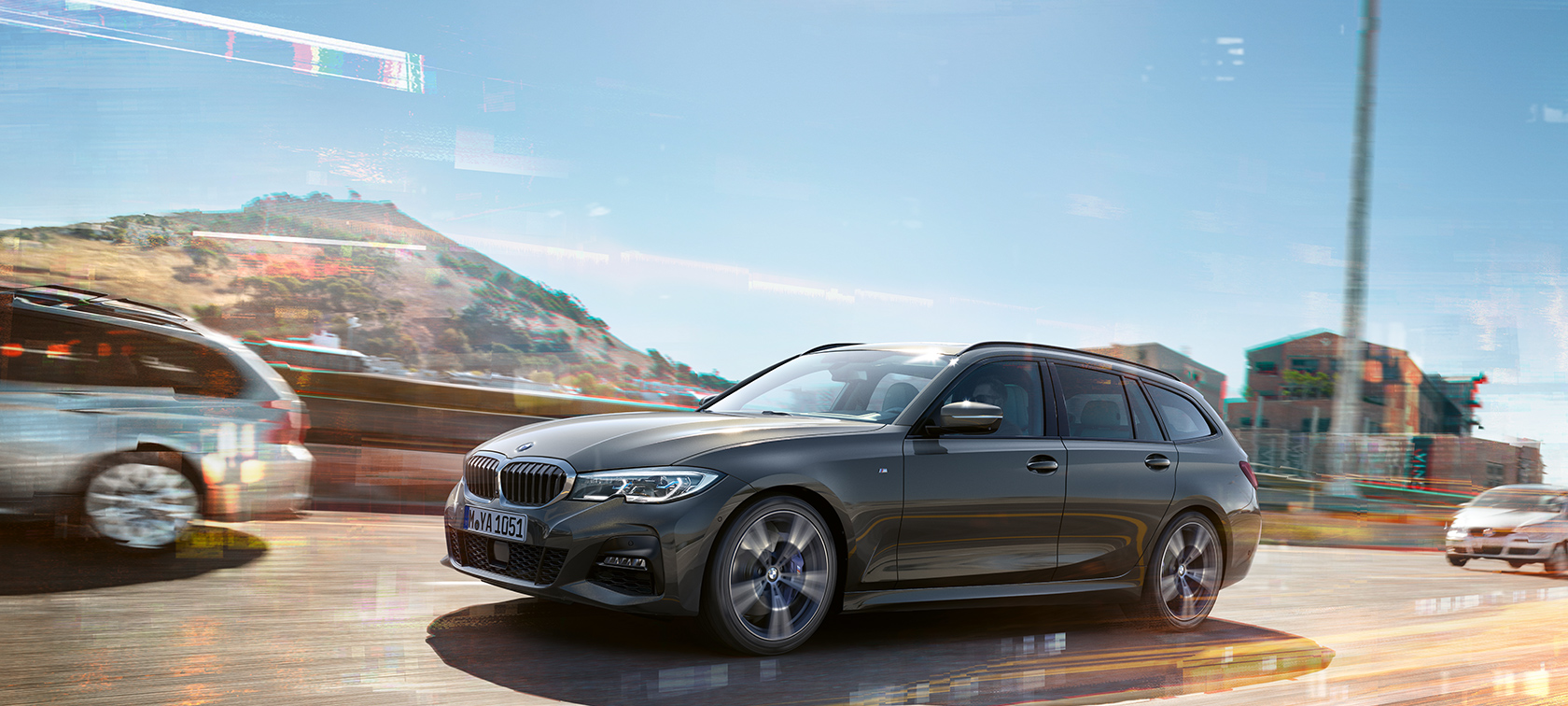 BMW 3 Series Touring, lateral driving shot BMW 3 Series Touring, lateral driving shot in front of houses and mountains in the background