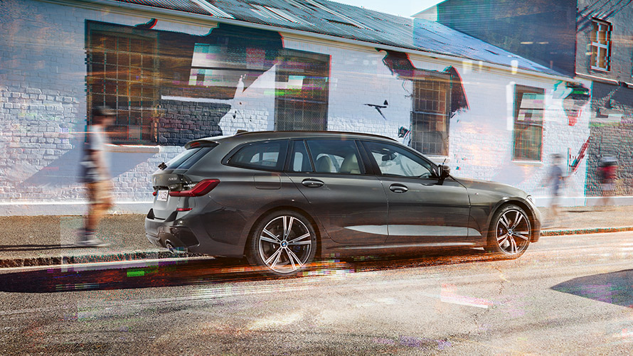 BMW 3 Serisi Touring (G21), Metalik Gri/Dravite, arka çaprazdan görünüm BMW 3 Serisi Touring (G21), Metalik Gri/Dravite, bir binanın önünden geçerken arka çaprazdan görünüm