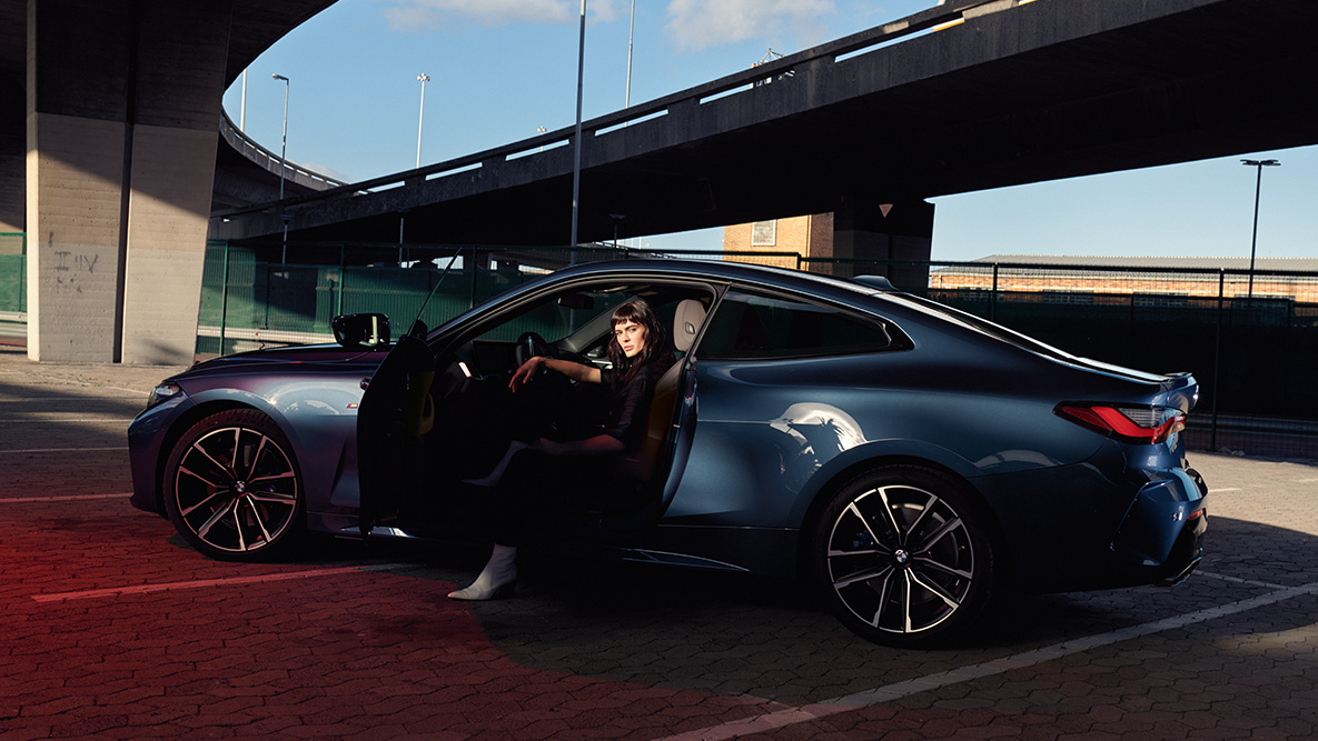 Yandan görünüm, hafif alaşım jantlar, BMW 4 Serisi Coupé G22 BMW 4 Serisi Coupé G22, Metalik Mavi/Arctic Race, içindeki modelle birlikte kapısı açık haldeki otomobilin yandan görünümü