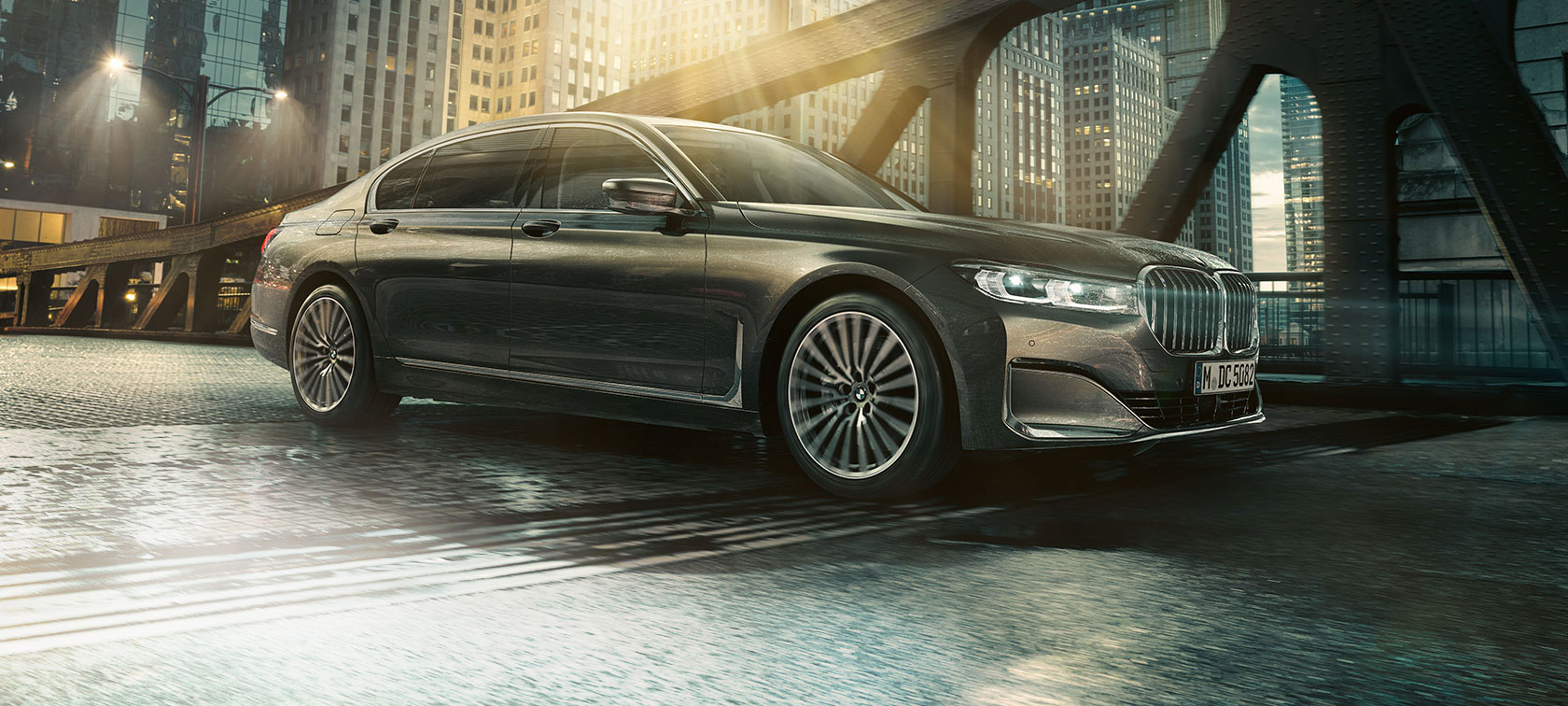 BMW 7 Serisi Sedan, yandan görünüm Aydınlatılmış bir otelin önünde BMW 7 Serisi Sedan‘ın kapısı açık halde yandan görünümü
