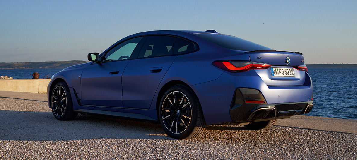 BMW i4 M50 G26, arka çaprazdan görünüm BMW i4 M50 G26, M Metalik Mavi/Portimao, rıhtımda arka çaprazdan görünüm