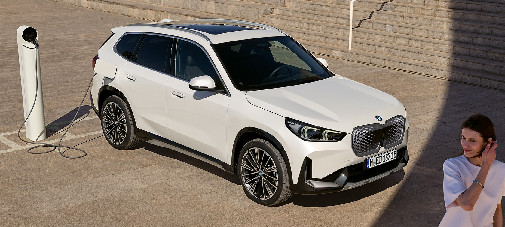 BMW iX1 U11 BEV, Şarj halinde yandan görünüm BMW iX1 U11 BEV, Metalik Beyaz/Mineral, Şarj halinde yan çaprazdan görünüm