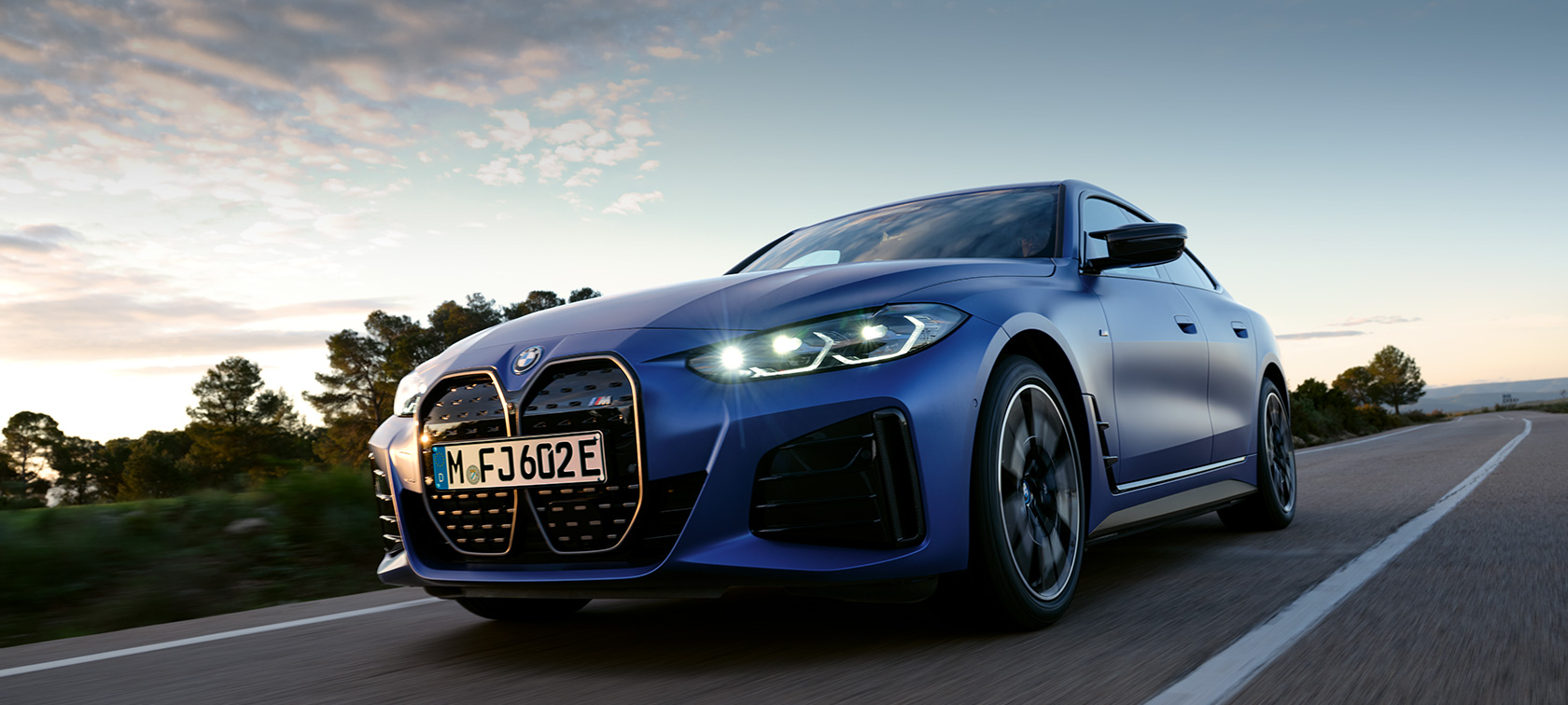 BMW i4 M50 G26, kayalık arazi önünde yandan görünüm BMW i4 M50 G26, BMW Individual Metalik Mat Mavi/Portimao, kayalık arazi önünde yandan görünüm