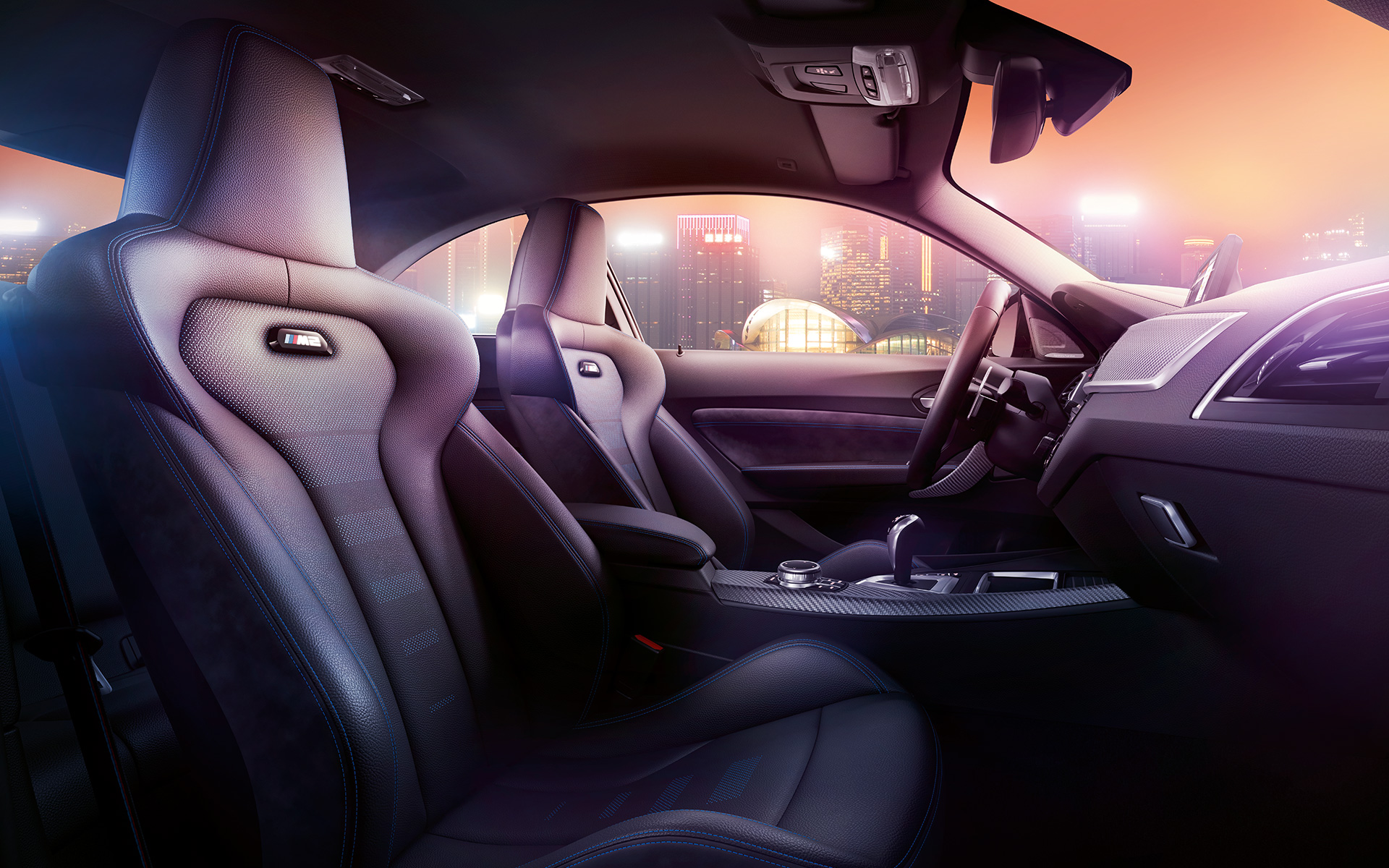 Yeni BMW M2 Competition Spor koltuklar Arka planda gece şehir manzarasıyla Yeni BMW M2 Competition’ın kokpiti ve M spor koltukları
