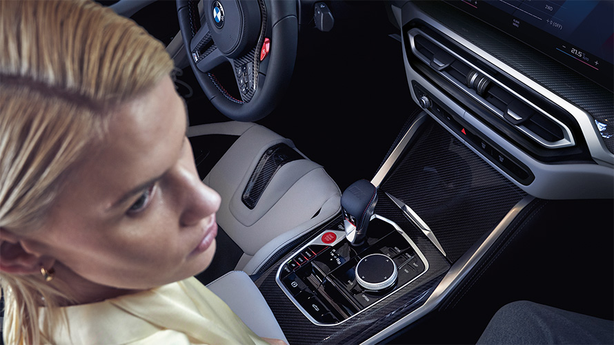 M xDrive özellikli BMW M4 Competition Cabrio G83, iç tasarım, merkez konsol M xDrive özellikli BMW M4 Competition Cabrio G83, merkez konsol ve sürücü koltuğunda oturan kadın
