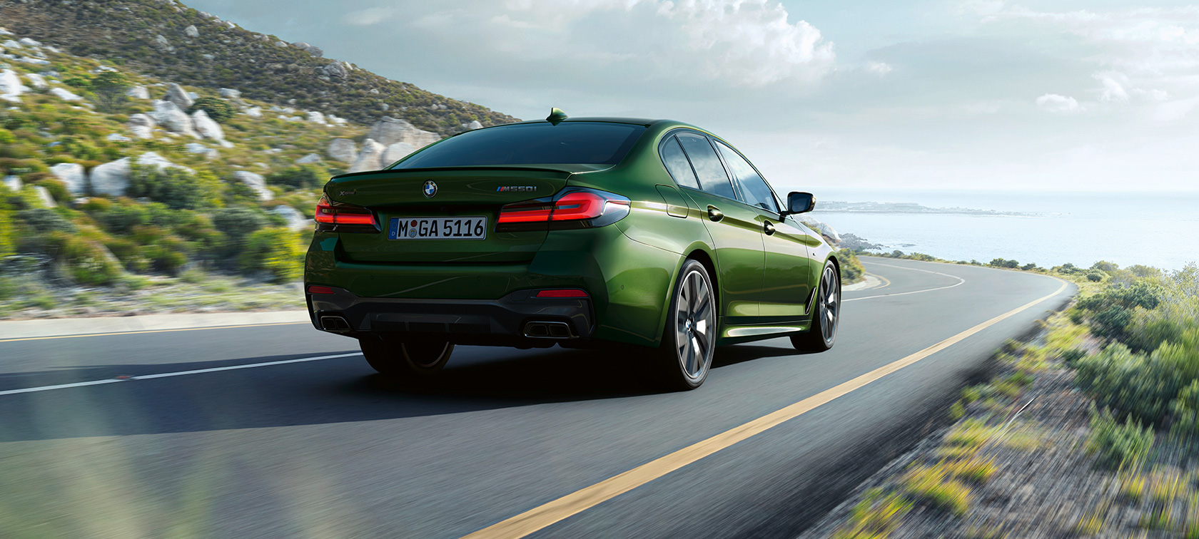 BMW M550i xDrive Sedan G30 LCI sürüş sırasında arkadan görünüm BMW M550i xDrive Sedan G30 LCI BMW Individual Metalik Yeşil/Verde Ermes sürüş sırasında arkadan görünüm