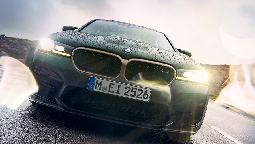 BMW M5 CS F90 Metalik Yeşil/Frozen Deep farlar açıkken önden görünüm