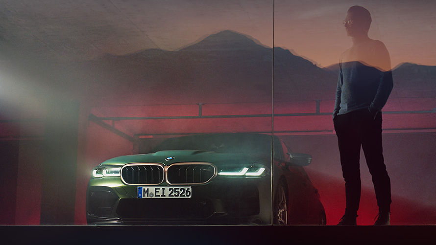 BMW M5 CS F90 otomobilin önünde duran adam ile önden görünüm BMW M5 CS F90 Metalik Yeşil/Frozen Deep otomobilin önünde duran adam ile önden görünüm