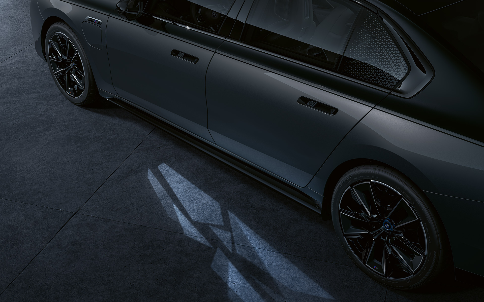 Işıklandırma konsepti, BMW M760e xDrive Sedan G70, BMW Individual Metalik Siyah/Sapphire BMW Individual Metalik Gri/Dravite iki tonlu gövde rengi, yandan görünüm, Işıklı Karşılama Halısı açıkken yakın plan çekimi