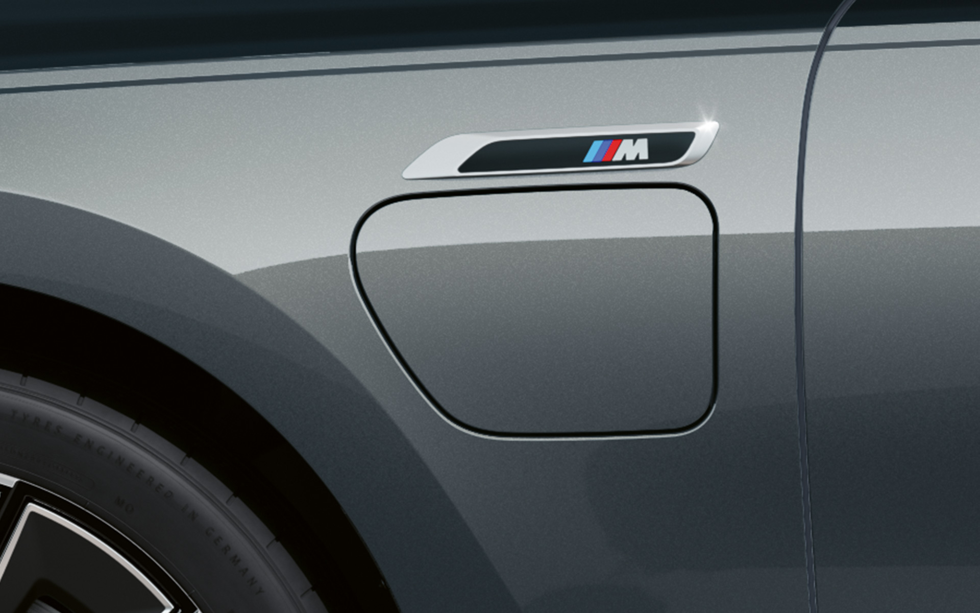 M amblemi, BMW M760e xDrive Sedan G70 M Performance, BMW Individual Metalik Siyah/Sapphire BMW Individual Metalik Gri/Dravite iki tonlu gövde rengi, yan görünümden yakın plan çekim