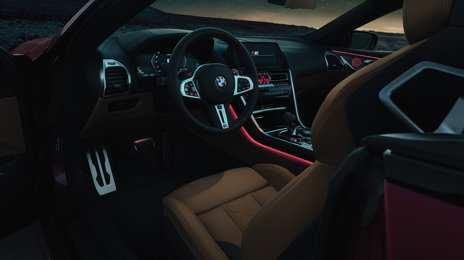 BMW M8 Competition Cabrio, M deri direksiyon ve kırmızı ortam aydınlatmasıyla kokpitin gece görünümü. BMW M8 Competition Cabrio, M deri direksiyon ve kırmızı ortam aydınlatmasıyla kokpitin gece görünümü.
