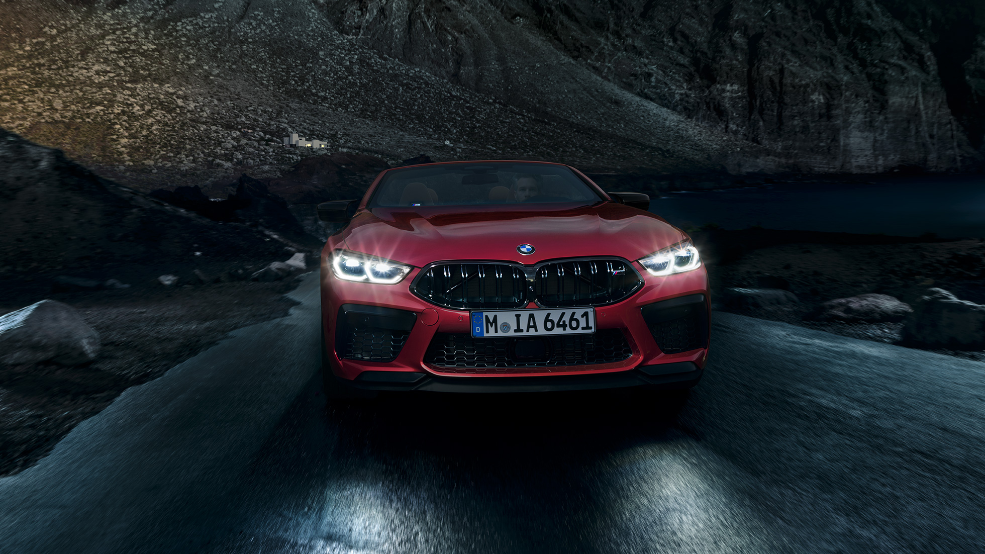 BMW M8 Competition Cabrio, önden görünüm. Gece sürüşü sırasında parlayan farlarıyla metalik Kırmızı/Motegi BMW M8 Competition Cabrio, önden görünüm.