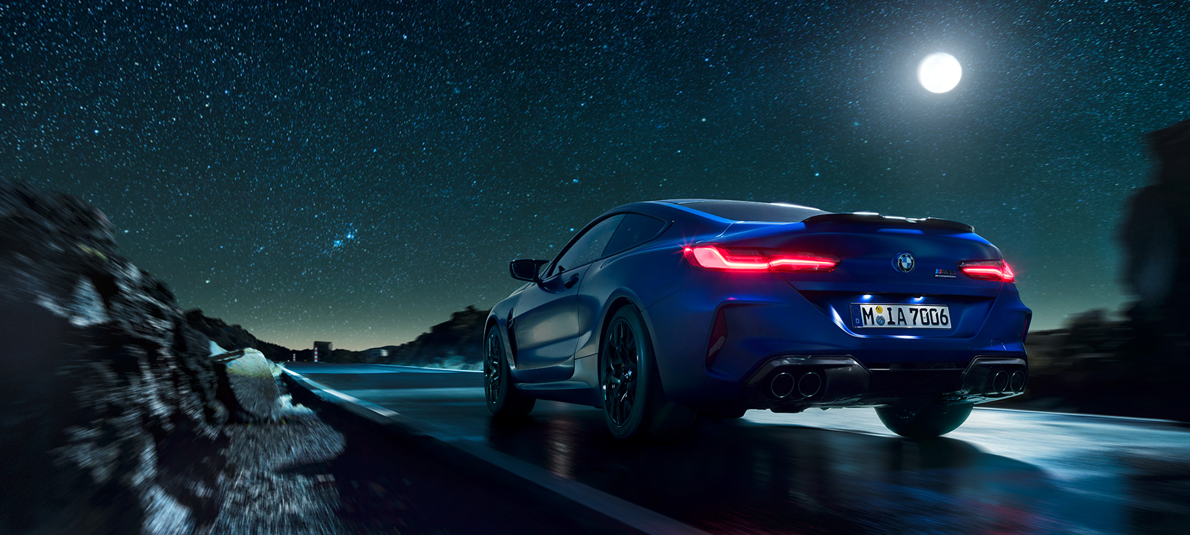 BMW M8 Competition Coupé, arkadan görünüm. BMW M8 Competition Coupé, dolunayda gece sürüşü sırasında arkadan görünüm.