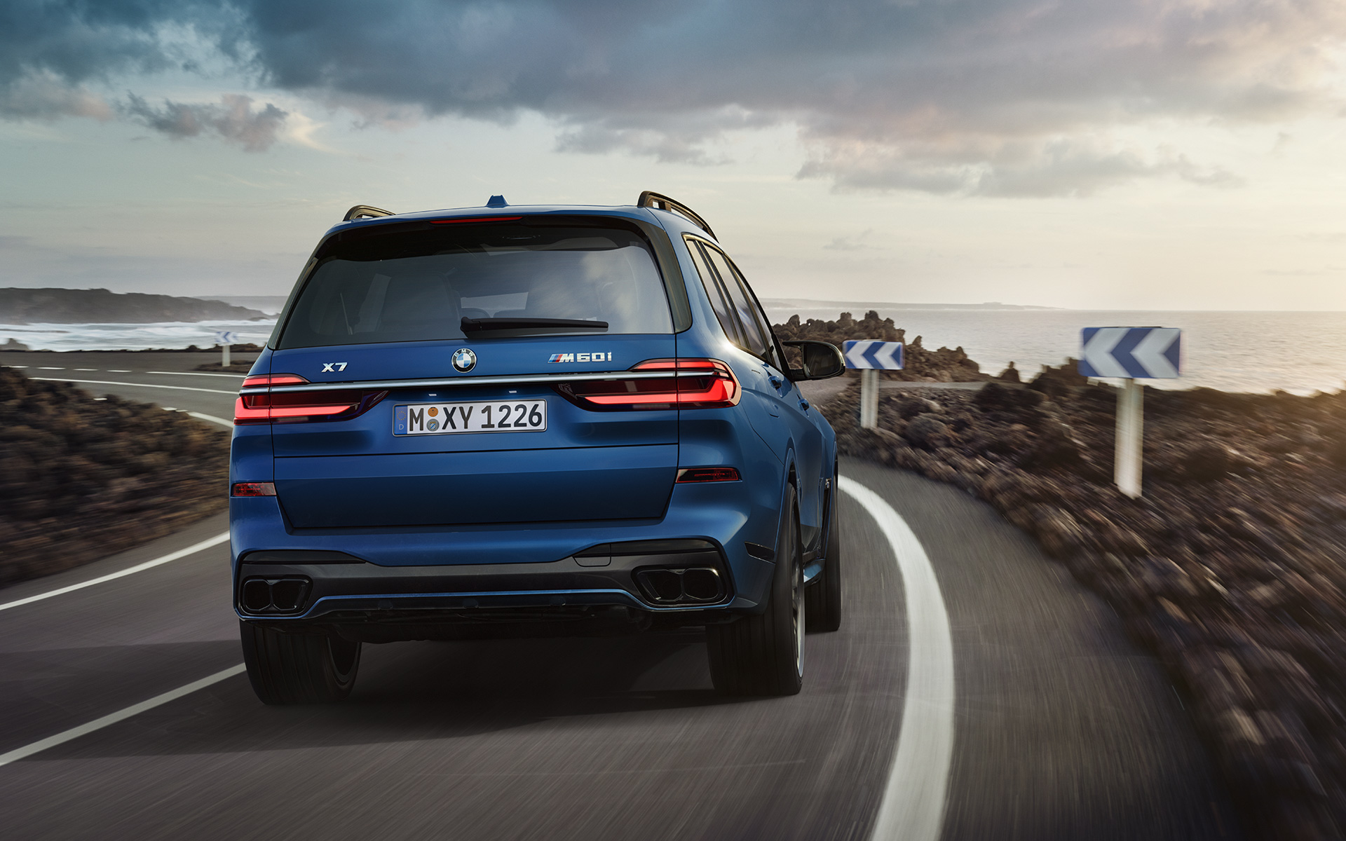 BMW X7 M60i G07 LCI, Metalik Mat Mavi/Marina Bay, sürüş sırasında arkadan görünüm