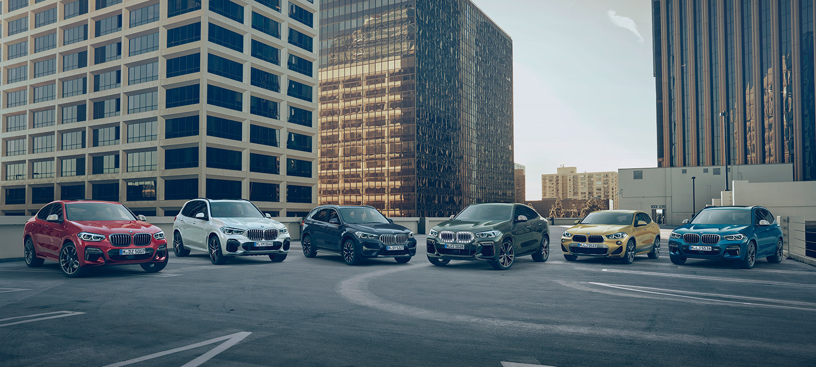 Binaların önünde yer alan bir katlı otoparkta park halindeki BMW X araçları BMW X Serisi, binaların önünde yer alan bir katlı otoparkta park halindeki BMW X araçları