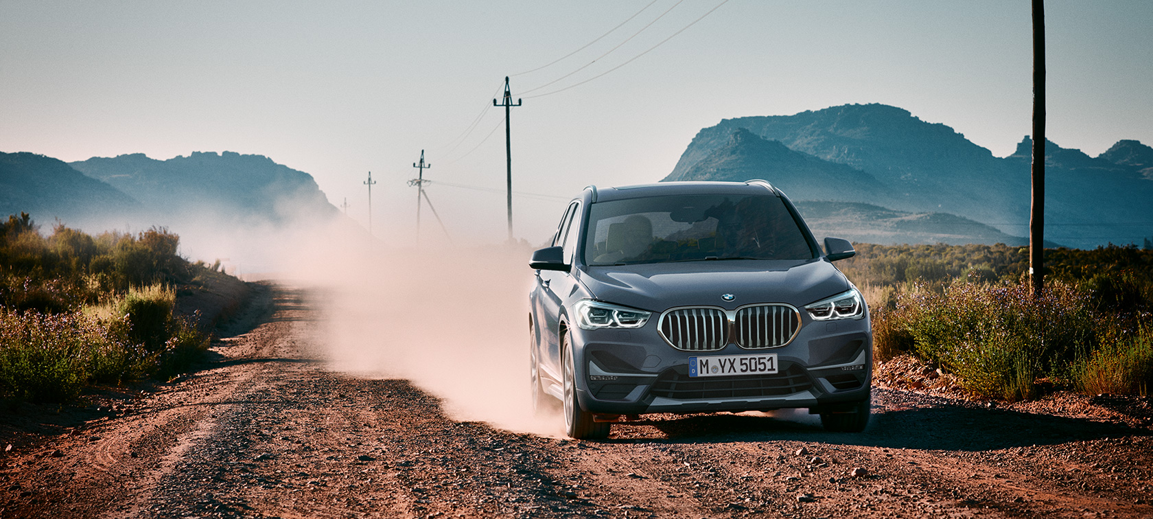 BMW X1, arkadan görünüm. BMW X1, dağ manzarası önünde seyir halinde, arkadan görünüm.