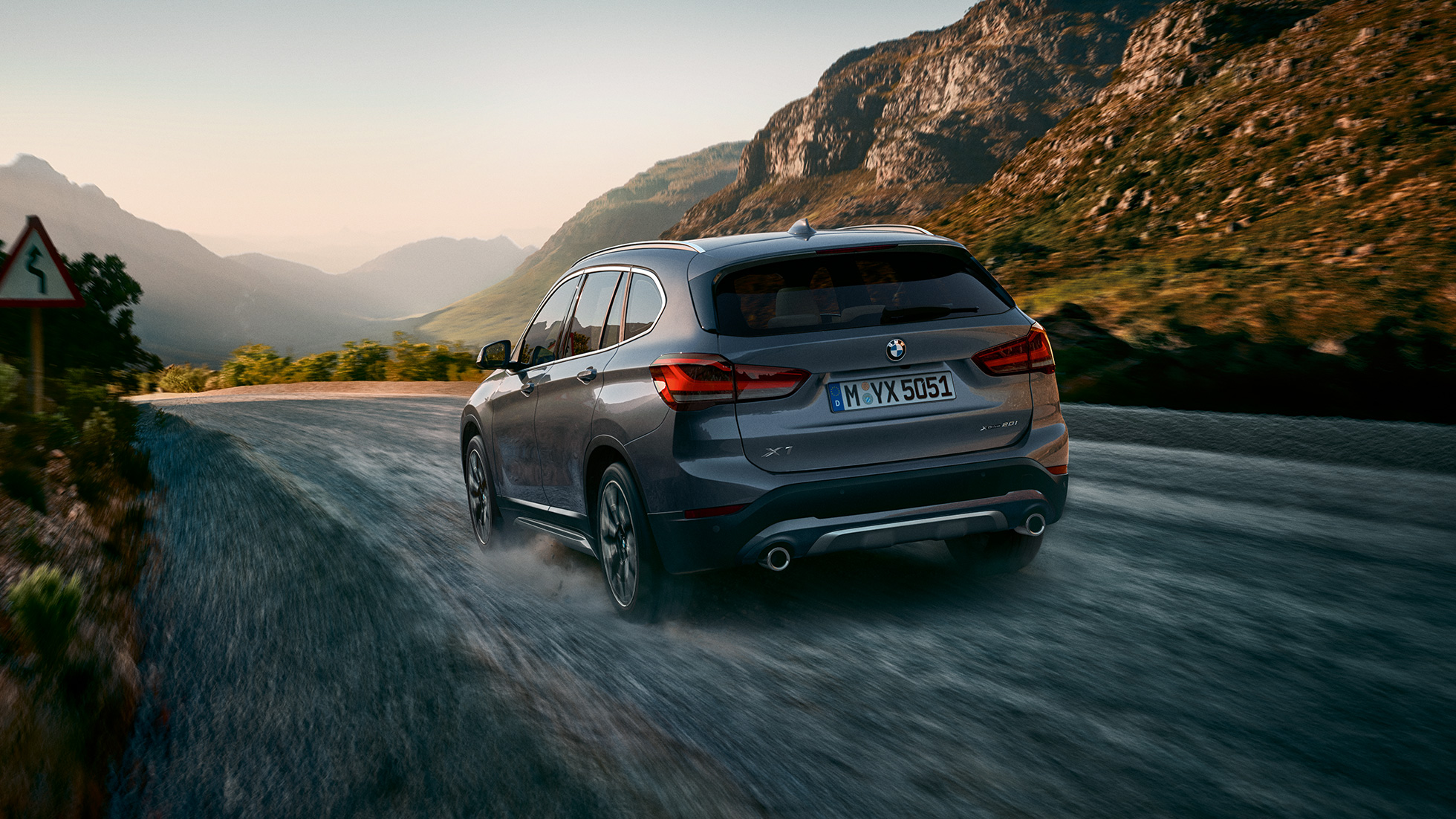 BMW X1, arkadan görünüm. BMW X1, dağ manzarası önünde seyir halinde, arkadan görünüm.