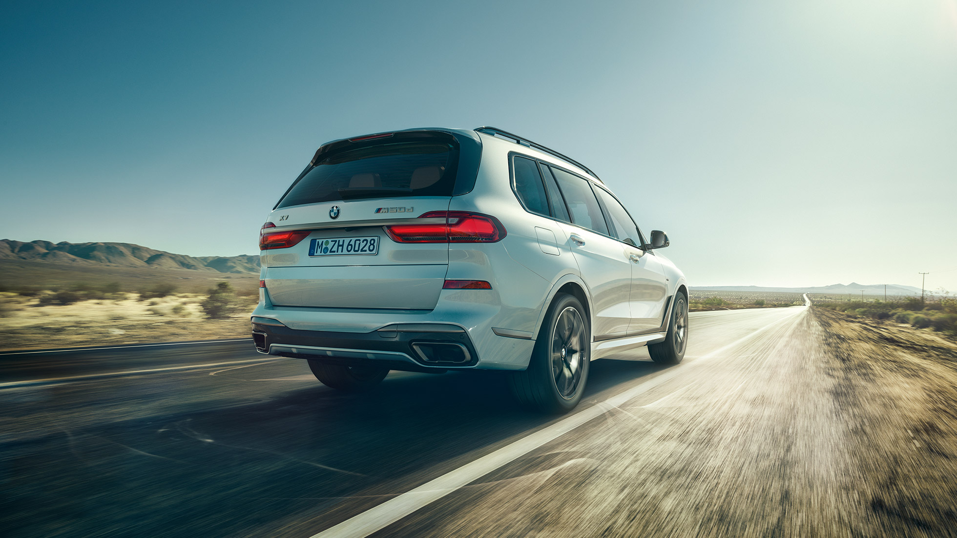 Yeni BMW X7 M50d, arkadan görünüm Metalik Beyaz renkte Yeni BMW X7 M50d sürüş halinde, arkadan görünüö