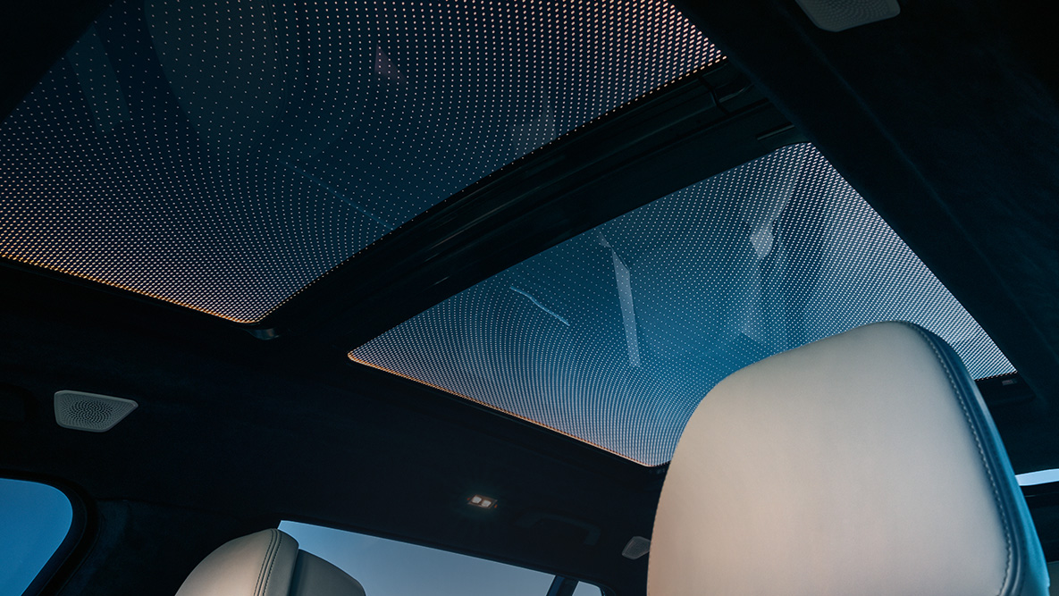 BMW X7 Ortam aydınlatması Turuncu ortam aydınlatmasıyla çevrelenmiş panorama cam tavana bakış