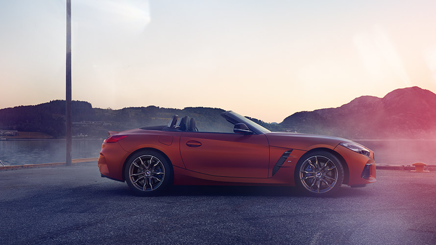 Turuncu renkte BMW Z4 First Edition virajda duruyor Dağ manzarası önünde virajda duran turuncu BMW Z4 First Edition