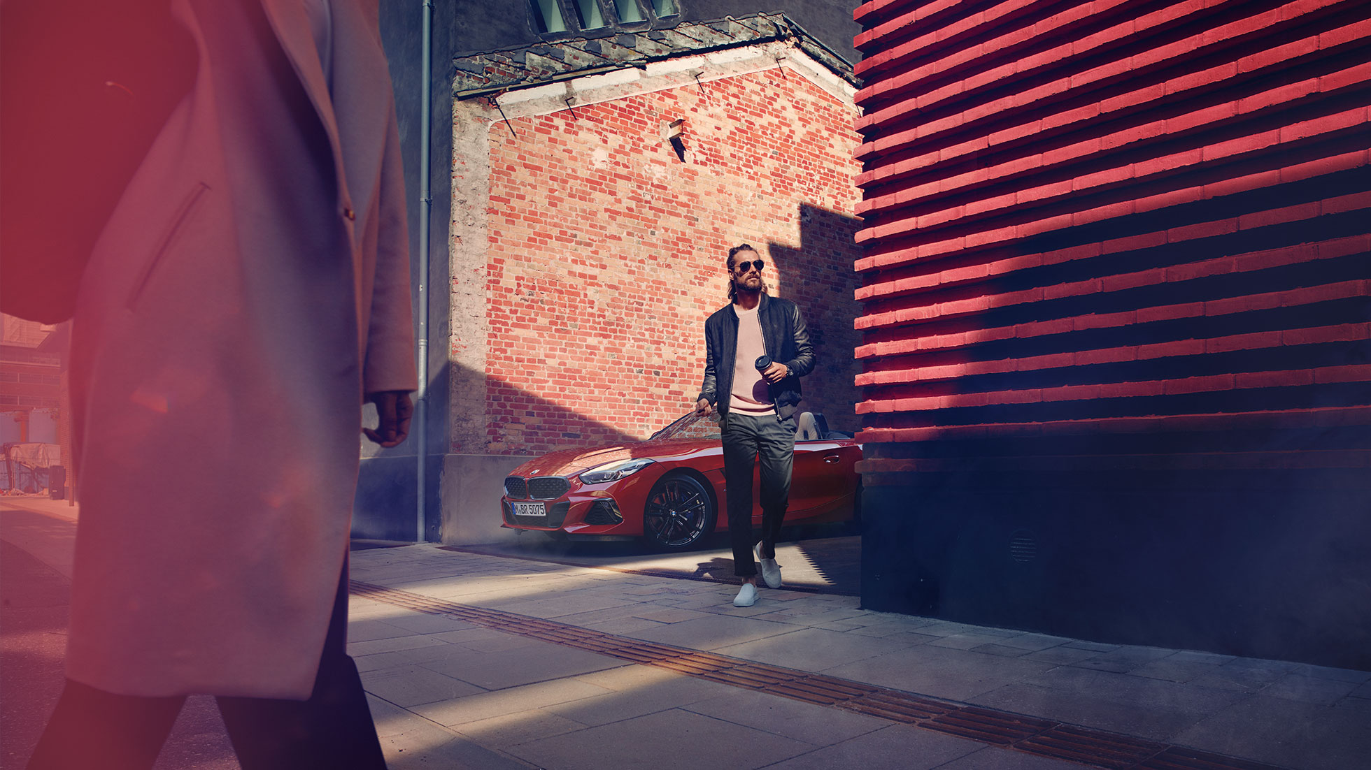 BMW Z4 Roadster bir ara sokakta Ara sokakta BMW Z4 Roadster’ın önünde bir erkek