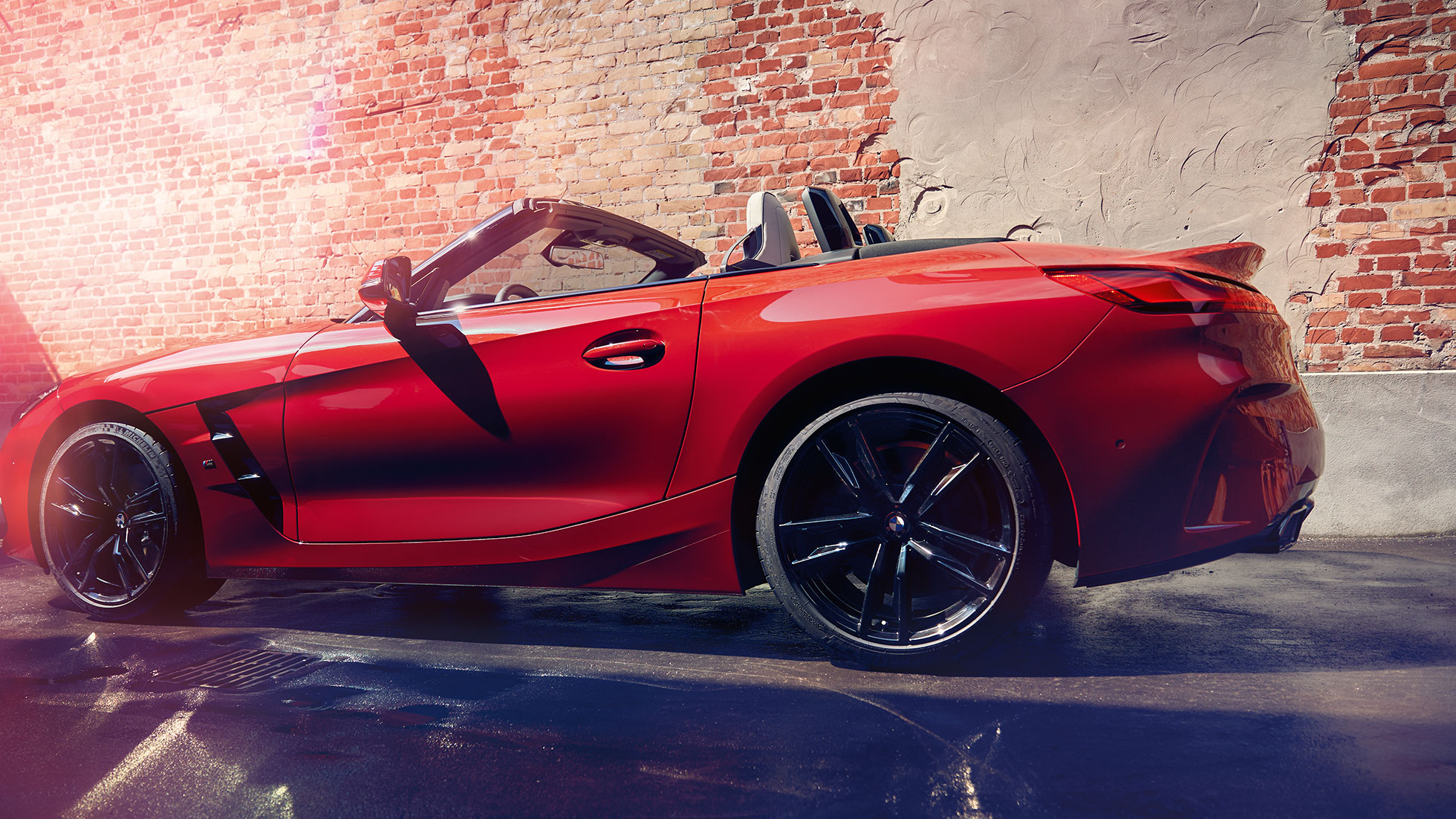 BMW Z4 Roadster’ın yandan resmi Tuğla duvar önünde BMW Z4 Roadster’ın yandan resmi