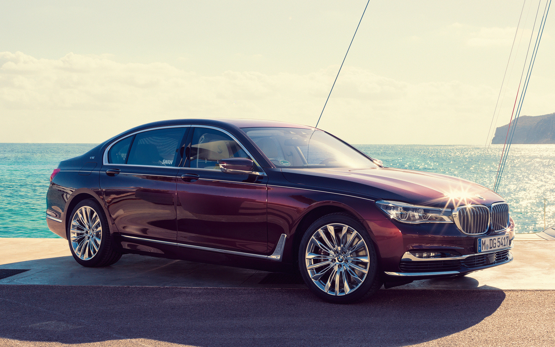 Nautor’s Swan’dan ilham alan BMW Individual M760Li G12, koydaki bir iskelede yelkenlinin önünde Nautor’s Swan’dan ilham alan BMW Individual M760Li G12, koydaki bir iskelede yelkenlinin önünde yan çaprazdan görünüm
